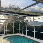 Peter's Pressure Washing technician cleaning a pool cage screen enclosure in Tampa Bay